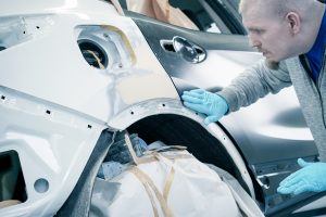 Ein Mitarbeiter bereitet ein Fahrzeug für die Lackierung vor.