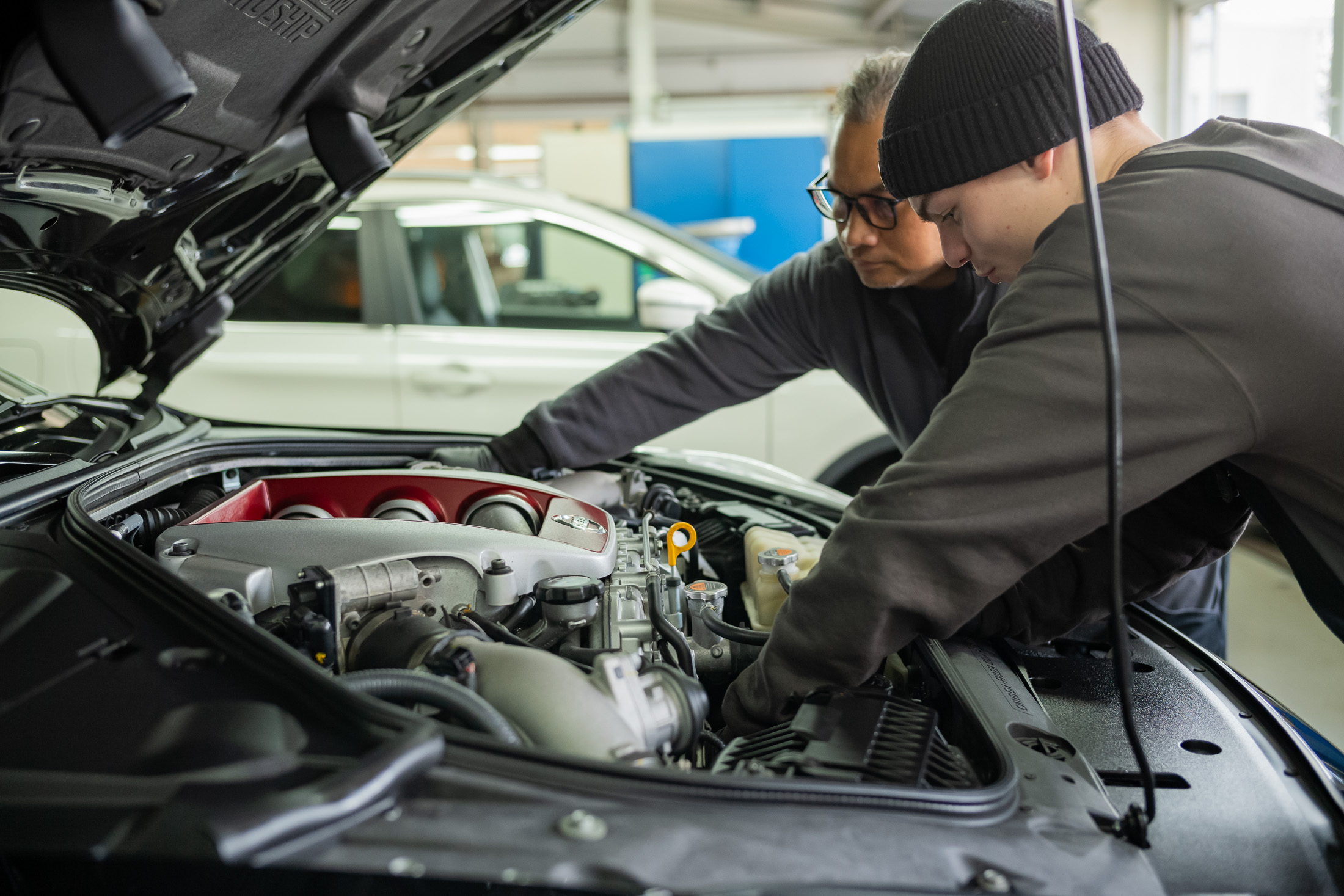 Zwei Miaterbeitende arbeiten im Motorraum eines Fahrzeuges.