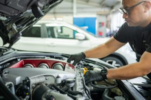 Ein Werkstattmitarbeiter kontrolliert die Motorfunktion eine Fahrzeuges.